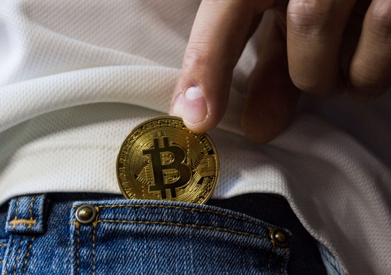 Hand putting gold bitcoin into back pocket