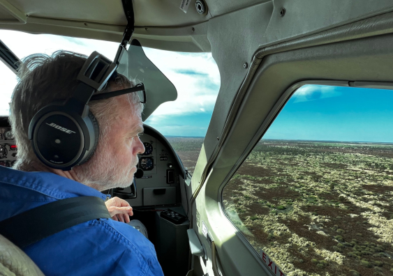 Richard Kingsford looks out the window of a light aircraft at marshes below