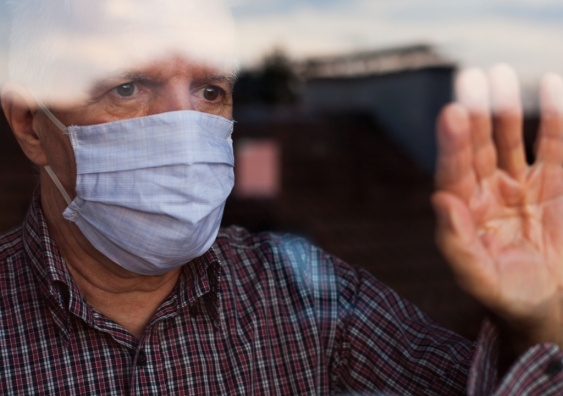 Senior man wearing face mask looking out window