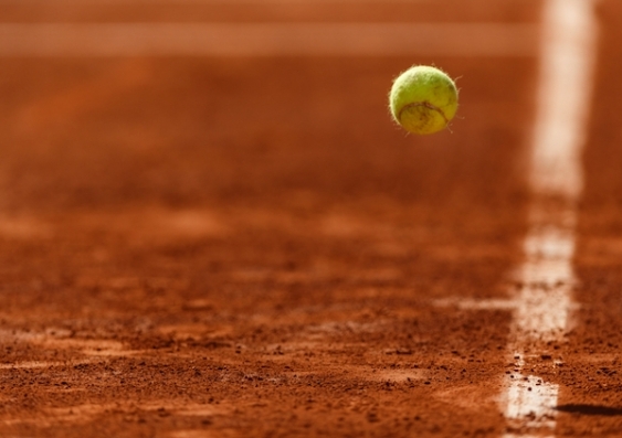 A tennis ball bounces on a clay court