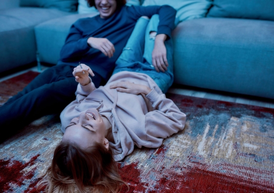 Young couple laughing while smoking a cannabis marijuana joint on a couch