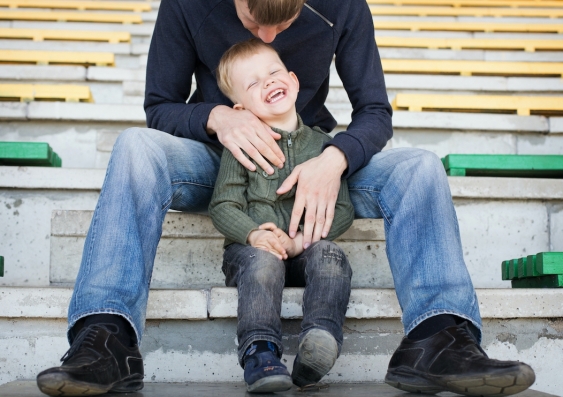 A man bending over and holding a laughing child