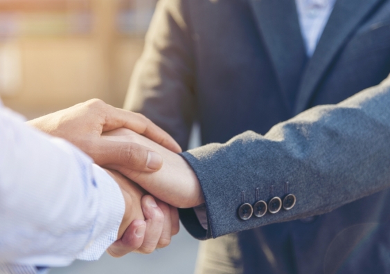 People dressed in corporate attire shaking hands.