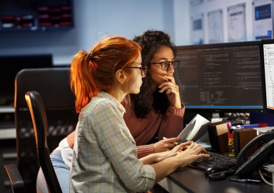 Two female software programmers looking at computer screens.