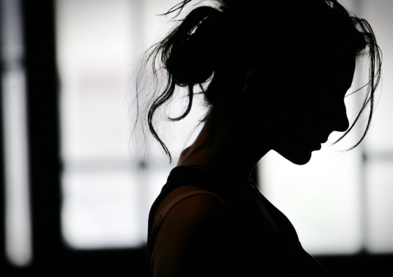 side angle silhouette of a woman standing in front of a window