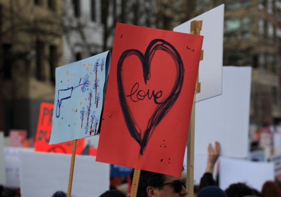 a red sign with a love heart at a protest