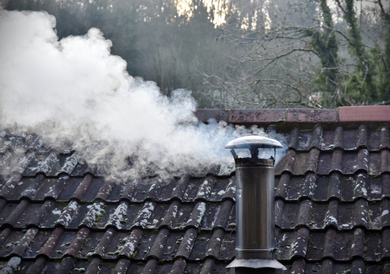 thick white smoke billows from a chimney during cold winter weather