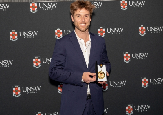 Dane Rampe with his Academic Excellence Award in front of the media wall