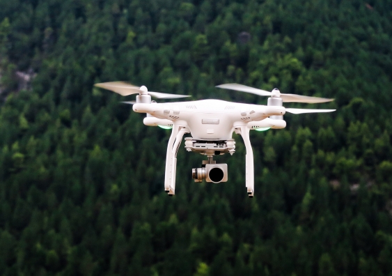 white drone flying in forest