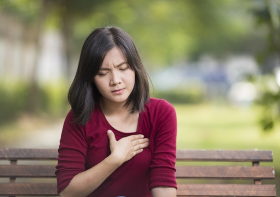 Woman on park bench clenching heart