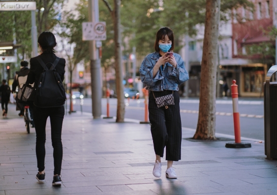 woman in face mask walking down the street during a coronavirus lockdown