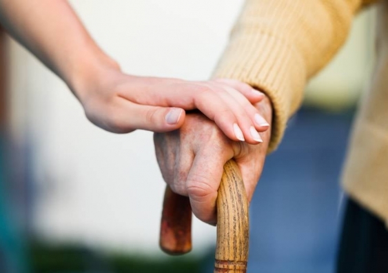 Nurse places hand over elderly woman's in aged care home