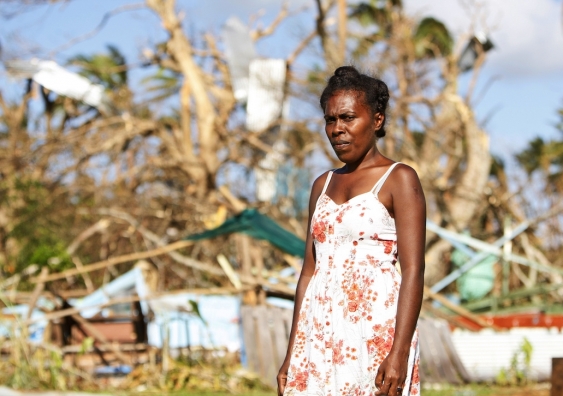 Woman stands in front of her destroyed home in Vanuatu