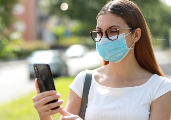 Woman using phone wearing face mask in public