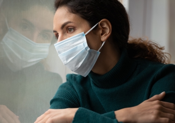 Woman wearing a face mask looking out of a window