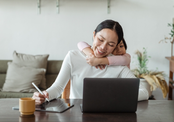 Woman working from home hugged by child