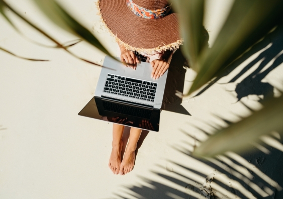 Woman working remotely on a laptop by the beach