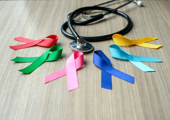 A collection of colourful charity ribbons signifying cancer awareness, pictured with a stethoscope.