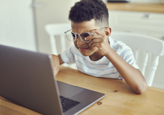 young person looks at the laptop screen with glasses