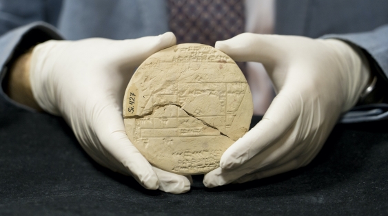 Daniuel mansfield carefully holds si.427, a tan, circular clay tablet about 25cm wide with markings on both sides