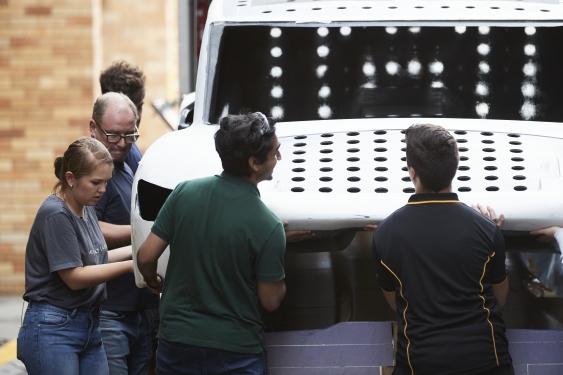 Members of the Sunswift team lift the chassis of the car