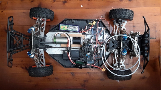 Top view of a miniature car chassis affixed with various electrical components