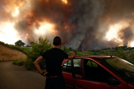 a man watches bushfire smoke soaring over the horizon