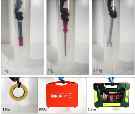 A robotic gripper lifts objects out of a tube and hooks onto other objects