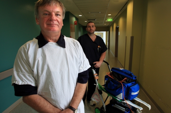 Professor Ken Hillman standing in hospital corridor with healthcare worker and MET trolley