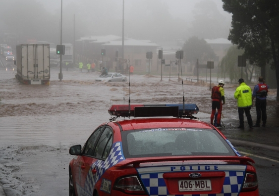 Emergency responders discuss options for rescuing a woman trapped on the roof of her car in flood waters during the 2010-2011 Queensland floods. (Credit: Timothy Swinson/Flickr)