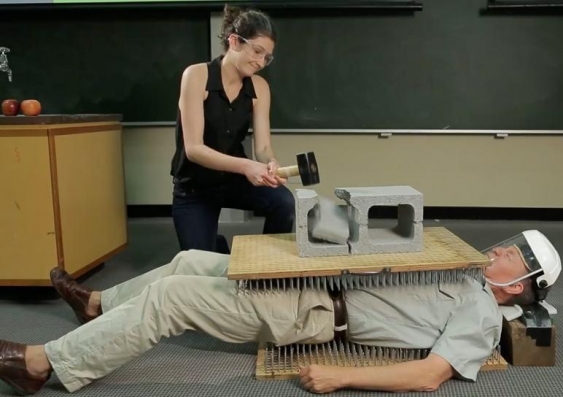 Don't do this at home ... A student breaks a brick on Professor Joe Wolfe to demonstrate the physics of collision. Photo: UNSW Physics
