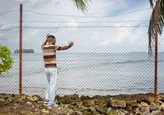 A Pakistani asylum seeker looks out over the ocean behind a wire fence in an offshore processing centre on Manus Island. Photo: Getty Images