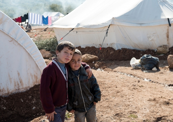Two boys stand in front of tents at a camp for displaced persons in northern Syria. Image: iStock