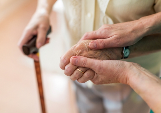 A nurse holding hands with an elderly person.