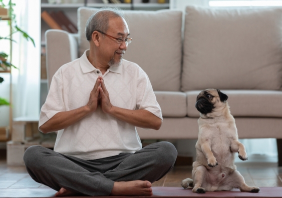 Dog owner meditating with their dog next to them.