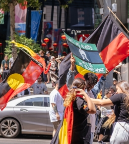 Protesters hold Aboriginal and Torres Strait Islander flags