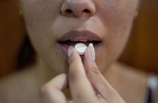 a woman places a pill into her mouth