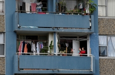 a woman stands on an apartment balcony crowded with clothes lines