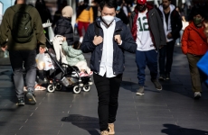 A man walking down a busy street with a face mask on