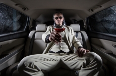 ostentatious man in a limousine holds out a glass of red wine