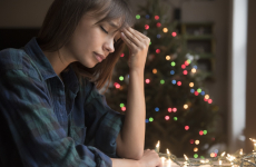 person with headache near christmas tree