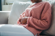 woman sitting on the couch and holding stomach