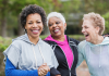 Three older women laughing in activewear at the park