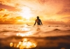 A surfer waits for a wave at sunset or sunrise