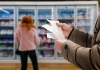 a person looks at a shopping docket in a supermarket aisle