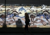 a woman walks past a mural with indigenous themes and native animals