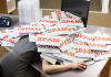 a worker at her desk buried under pieces of paper that say spam