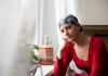 a young adult cancer patient wearing a headscarf sitting by the window