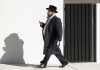 an orthodox jewish man walks down a street in traditional clothing