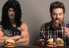 Caveman dressed in animal skins eats burger with modern human man